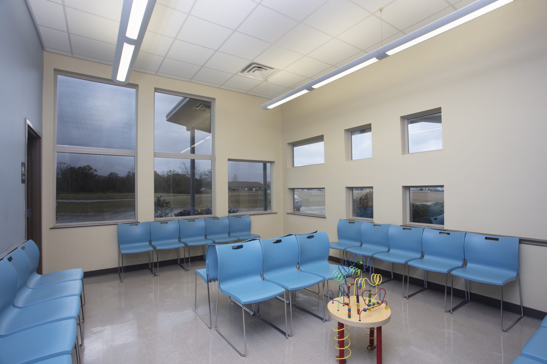 Waiting room with bright blue chairs and multiple windows