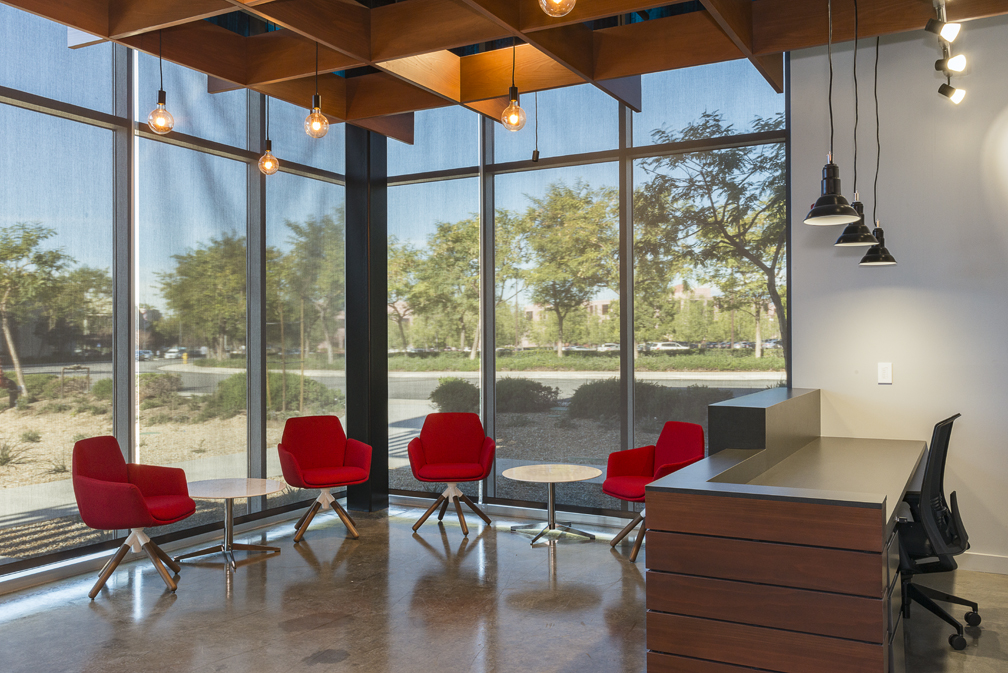 Reception area with large windows and bright red chairs.