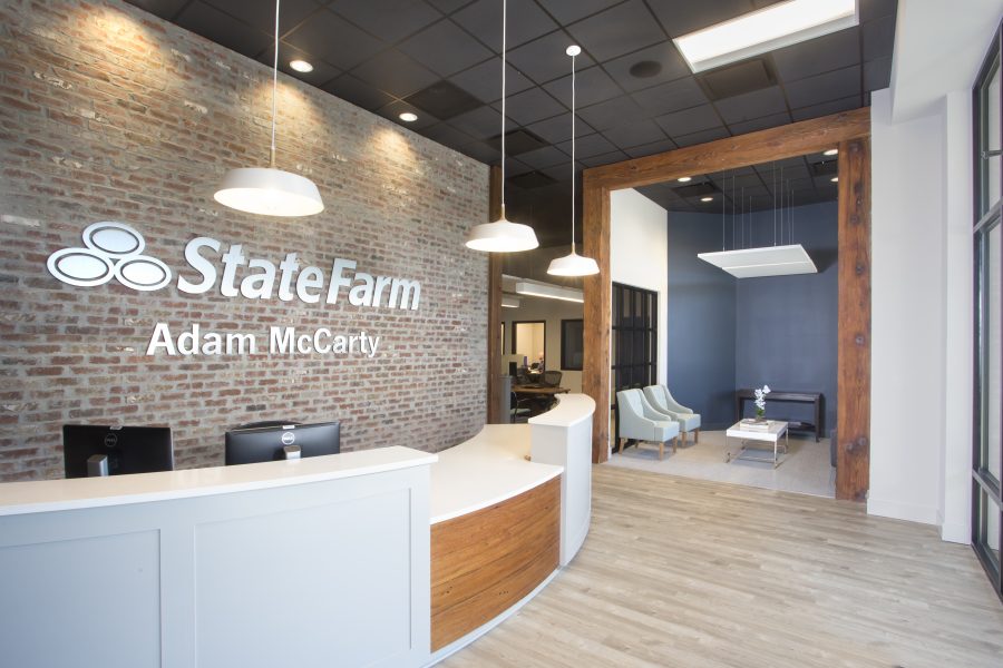 Adam McCarty front desk with exposed brick. Looks into the rest of the office with drop down lights and black ceilings.