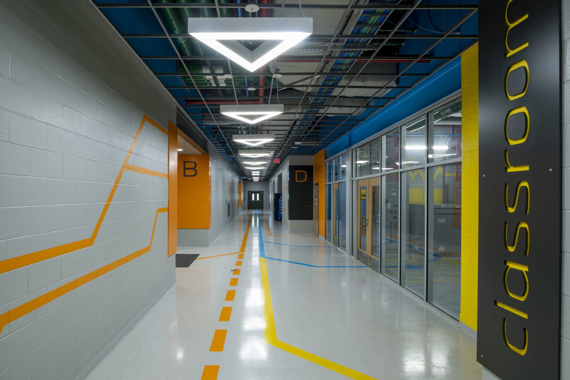 Hallway with triangle light fixtures and linear graphics on walls and floor