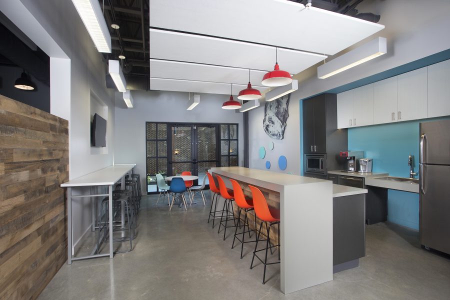 Bright break room with colorful chairs and red pendant lights